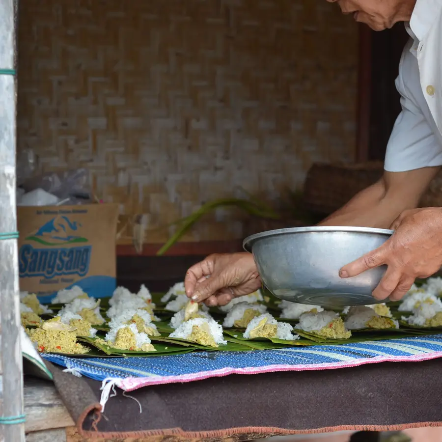 Tangan menyiapkan nasi bungkus daun pisang