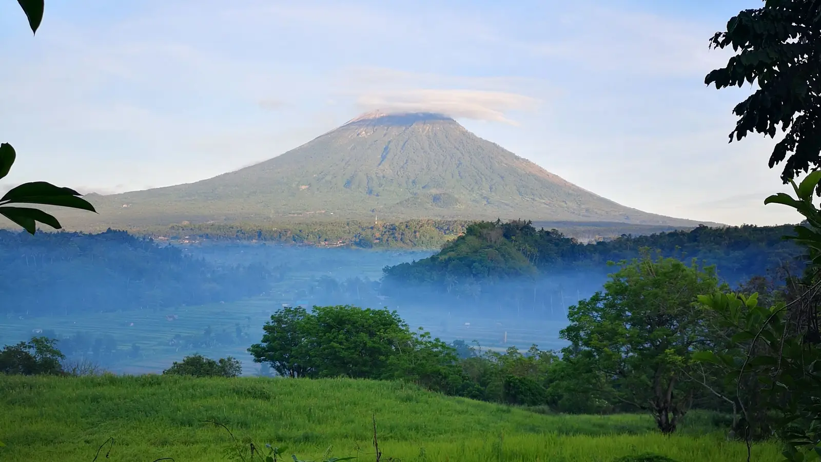 Mount Agung seen across green hills in East Bali